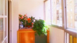 Eine Ecke mit einem Fenster, einem Holzschrank und einem Blumentopf.