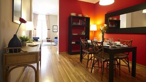 A dining area with a wooden table and chairs, a bookshelf, and a mirror on the wall.