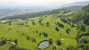 A golf course with a pond, trees, and a building in the distance. - Ancient country villa with pool in the hills of Tuscany, surrounded by woods  (Poppi)