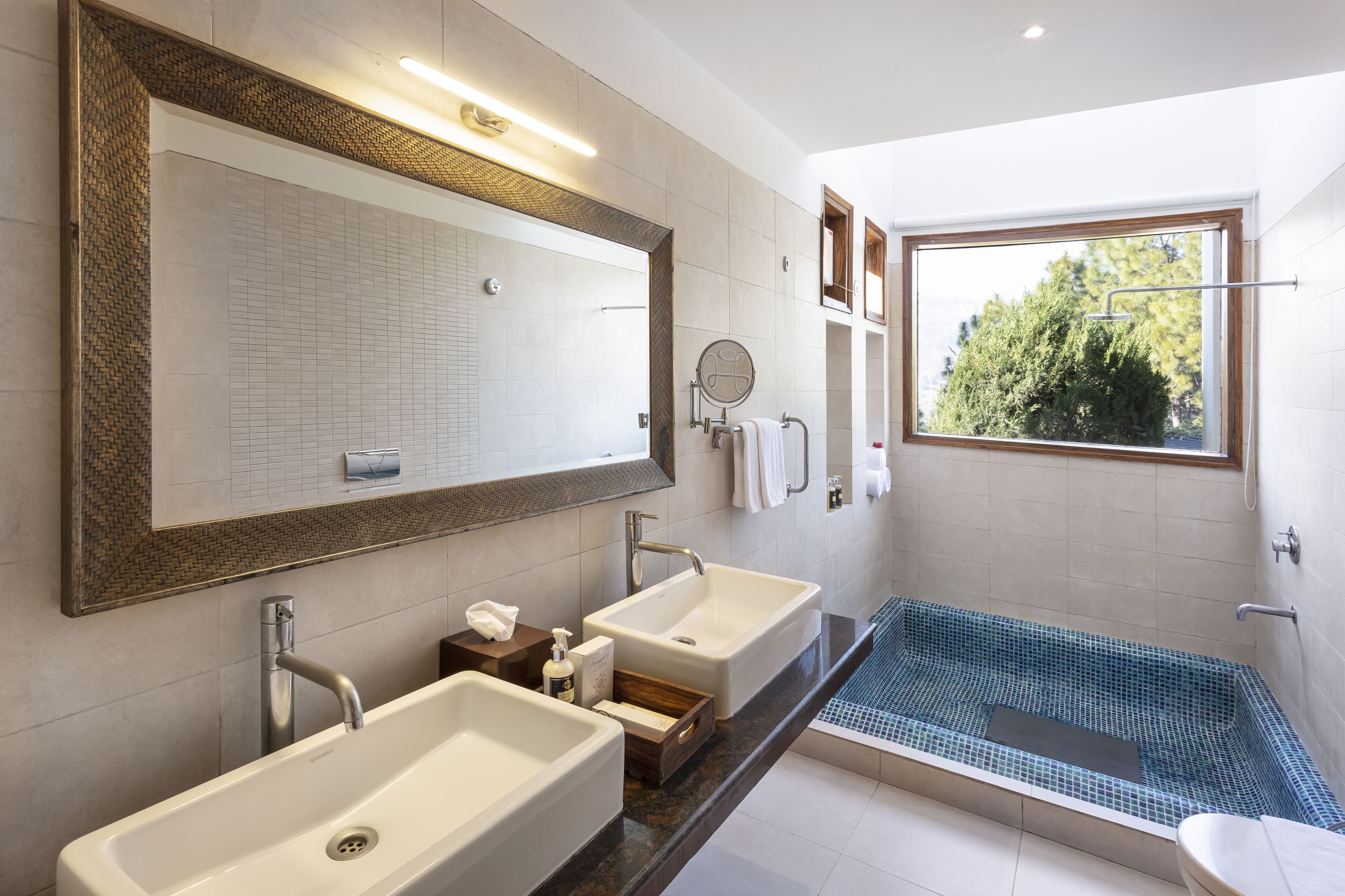 A modern bathroom with two sinks, a bathtub, and a large mirror.