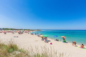 Ein Strand mit vielen Sonnenschirmen und Menschen, die die Sonne genießen.