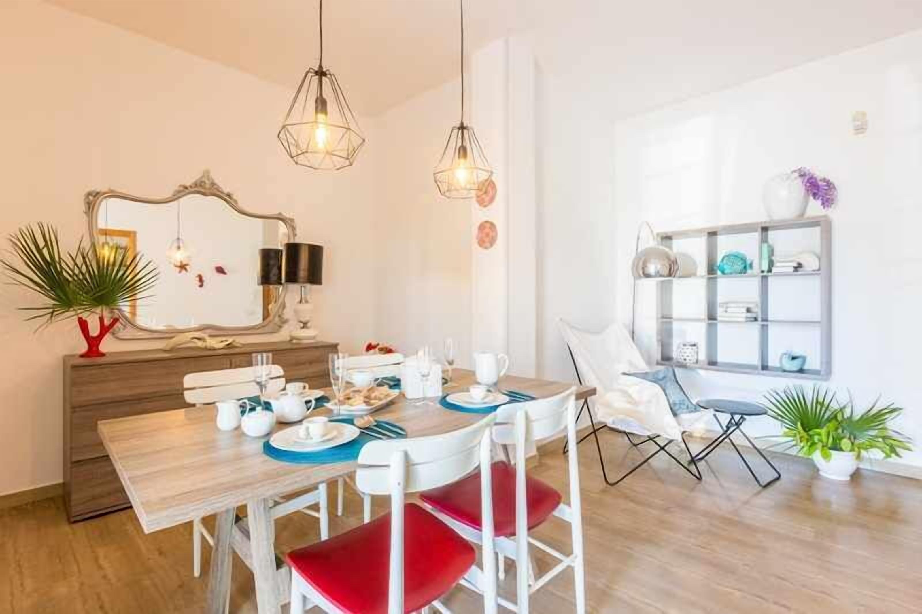 A dining area with a wooden table, red chairs, and hanging lights.