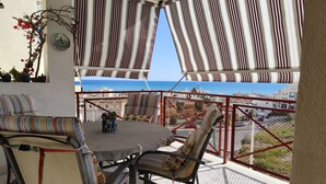 A balcony with striped curtains, a table, chairs, and a view of the sea. - Apartment in private urbanization with pool and garden area in Santa Pola (Santa Pola)