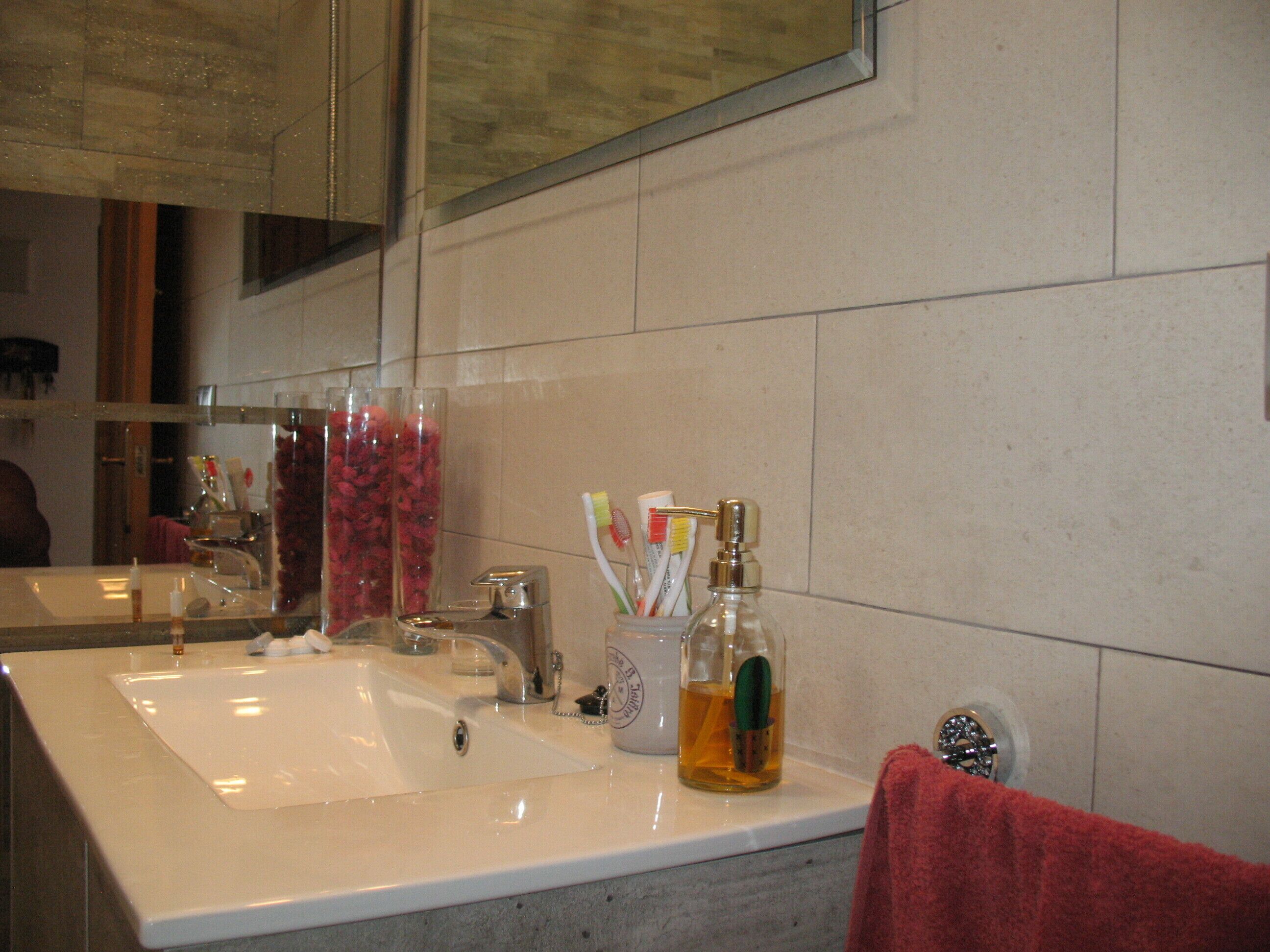 A bathroom with a large mirror, two sinks, and various toiletries.