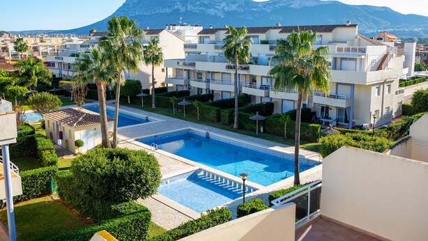 A resort with a swimming pool, palm trees, and mountain views. - Maravilloso Ático a tan solo 150 m de la playa. Wifi. A/A. 5 pers. (Dénia)