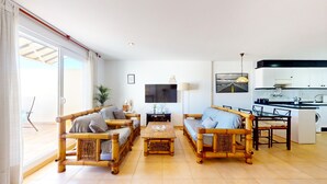 A spacious living room with a large TV, a dining area, and a kitchen. - Maravilloso Ático a tan solo 150 m de la playa. Wifi. A/A. 5 pers. (Dénia)