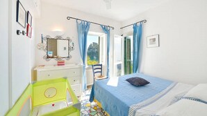A bedroom with a bed, a dresser, a mirror, and a window with curtains. - Cottage by the Sea in Cartaromana Bay, with a View of Aragonses Castle  (Ischia)