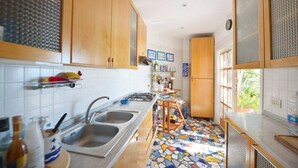 A kitchen with wooden cabinets, a tiled backsplash, a double sink, and a colorful mosaic floor. - Cottage by the Sea in Cartaromana Bay, with a View of Aragonses Castle  (Ischia)