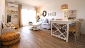 A living room with a white sofa, a dining table, wicker baskets, and a wall with framed pictures and a motivational quote.