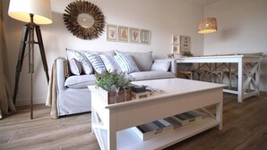 A living room with a sofa, a coffee table, a floor lamp, and a wall-mounted mirror.