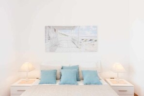 A bedroom with a bed, two bedside tables, and a wall-mounted painting.