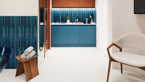 A modern kitchen with blue cabinets, a white countertop, and a wooden stool with towels. - Casa Pina Ocean (Sorrento)