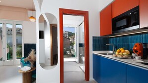 A modern kitchen with blue cabinets, a black microwave, and a fruit bowl on the counter. - Casa Pina Ocean (Sorrento)