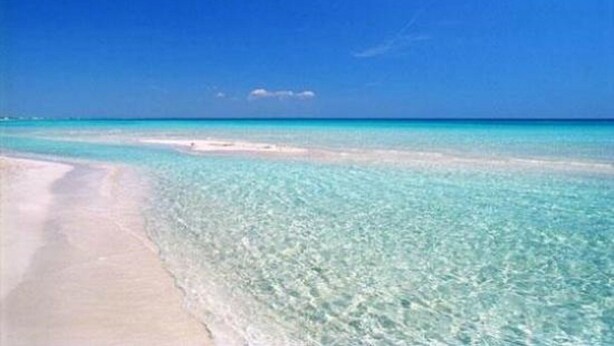 Een strand met helder turquoise water en een zandstrand.