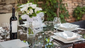 Ein Tisch, gedeckt für eine Mahlzeit, mit einer Weinflasche, einem Glas und einer Vase mit Blumen.
