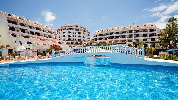Una piscina con un puente, rodeada de edificios de varios pisos con balcones.