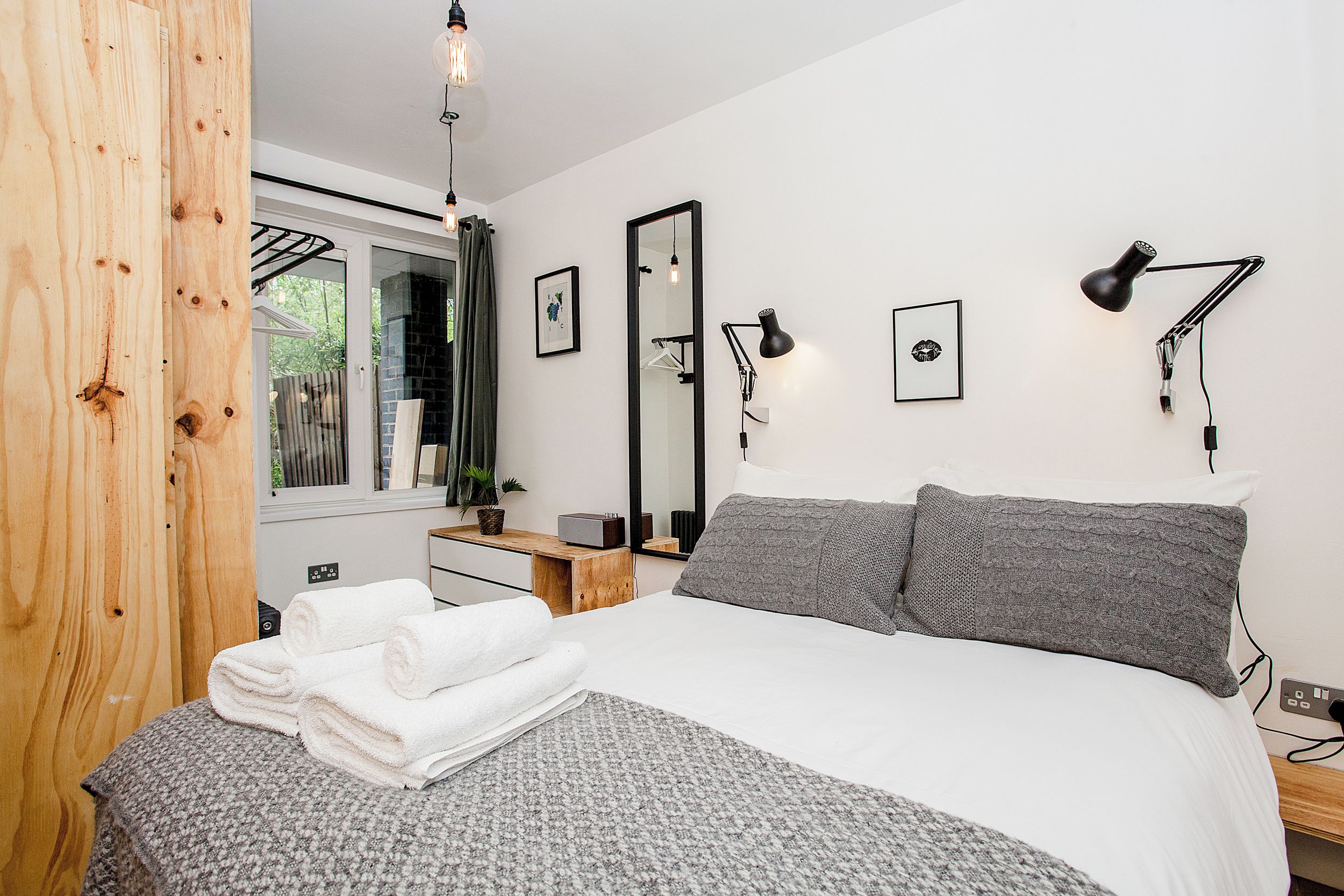 Une chambre à coucher avec un lit, deux lampes de chevet, un miroir et une fenêtre.