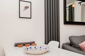 A modern dining area with a marble table, a decorative bowl, and a framed feather on the wall.