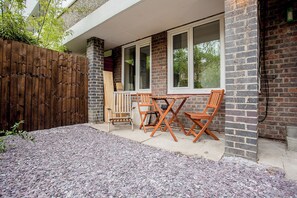 A patio with a wooden table and chairs, a brick wall, and a wooden fence.
