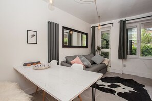Un salon moderne avec une table blanche, un canapé gris et un tapis noir et blanc.