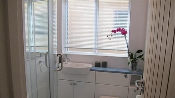 A small bathroom with a toilet, sink, and shower. - 'Seaminder' Beach Holiday Apartment (Bournemouth)