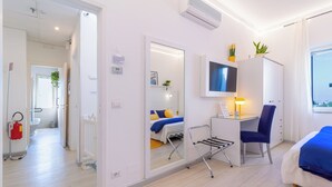 Une chambre d’hôtel moderne équipée d’un lit, d’un bureau, d’une chaise et d’un téléviseur fixé au mur.