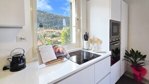 Une cuisine moderne avec une fenêtre, une bouilloire, un four à micro-ondes et une plante en pot.