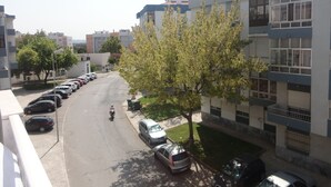 Eine Wohnstraße mit parkenden Autos und einem von Bäumen gesäumten Bürgersteig.