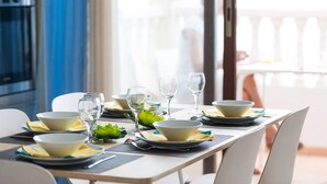A dining table set with bowls, plates, and glasses, with a view of a balcony and a building in the background. - Beautiful apartment in front of the beach (El campello)