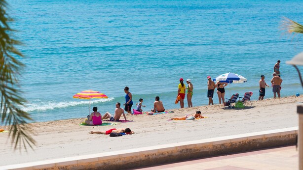 Une plage où des gens se prélassent au soleil et se baignent.