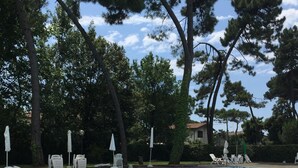 A swimming pool with lounge chairs and umbrellas, surrounded by trees. - VerdeCielo in Marina di Massa, Eliana's cottage  (Marina di Massa)