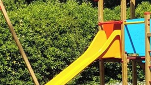 A playground with a yellow slide, wooden play structures, and picnic tables. - VerdeCielo in Marina di Massa, Eliana's cottage  (Marina di Massa)