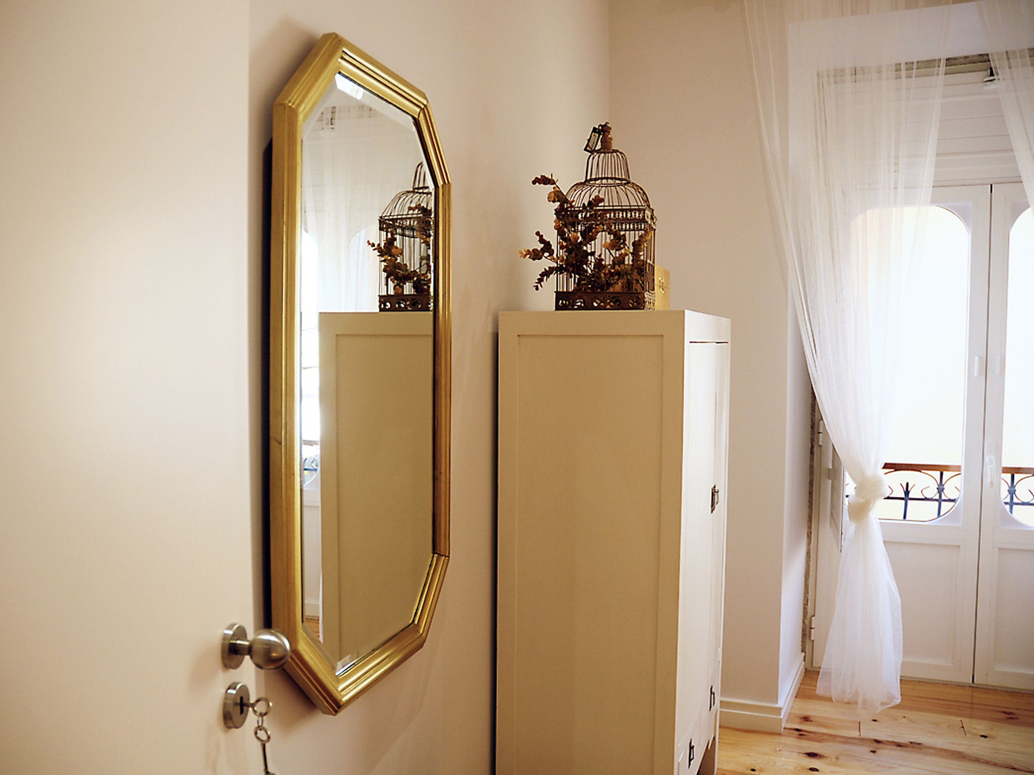 Una habitación con un espejo grande, un armario y una ventana con cortinas.