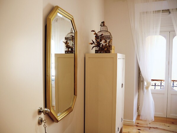 A room with a large mirror, a wardrobe, and a window with curtains.
