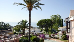 Zona residenziale con vista mare, caratterizzata da palme, un giardino fiorito e architettura tradizionale.