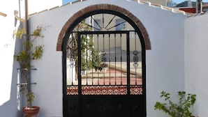 A gated entrance with a decorative arch, a potted plant, and a tiled patio area. - Kayenne 2 ,2 bedroom self catering apartment (Iznajar)