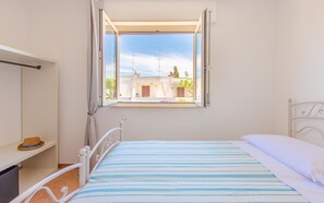 Une chambre à coucher avec un lit, une fenêtre et une vue sur les bâtiments environnants.