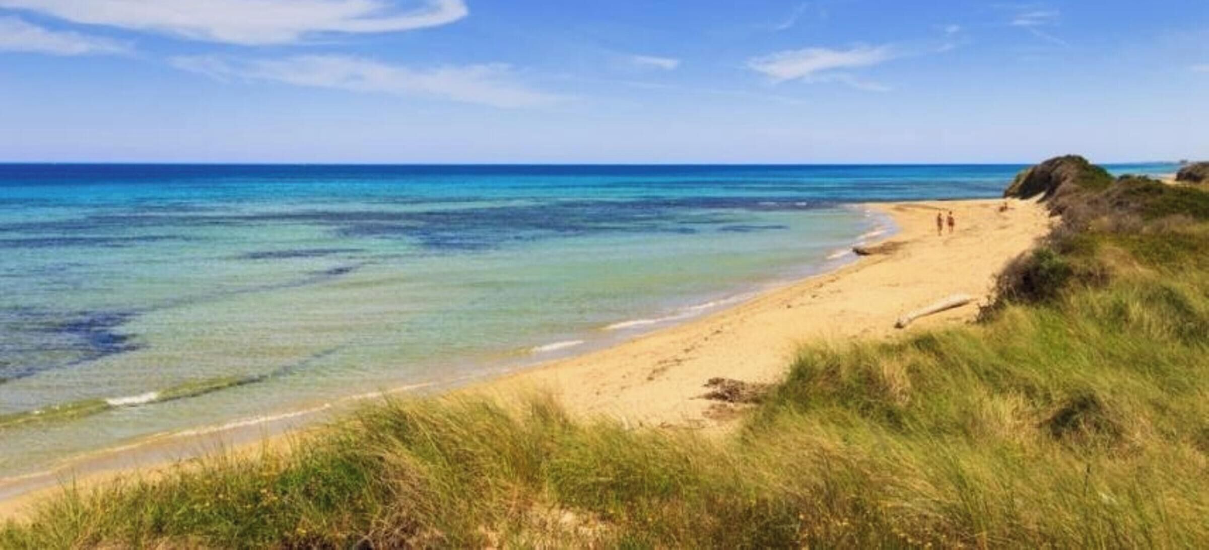 Una spiaggia con acqua cristallina e una battigia sabbiosa.