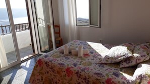 A bedroom with a bed, floral bedspread, and a view of the sea through a sliding glass door. - House in Calan Morell with garden, private pool and BBQ 300 m from the beach (ciudadela de menorca cALAN morell)