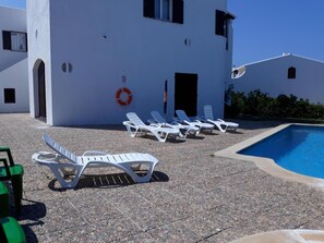 A poolside area with white lounge chairs and a pool. - House in Calan Morell with garden, private pool and BBQ 300 m from the beach (ciudadela de menorca cALAN morell)