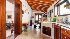 Una cocina con vigas de madera, zona de comedor y vistas al jardín.
