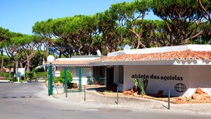 Ein Gebäude mit einem Schild, auf dem 'aldeia das acoletas' steht, und einem von einer Mauer umgebenen Außenbereich mit Tischen und Stühlen.
