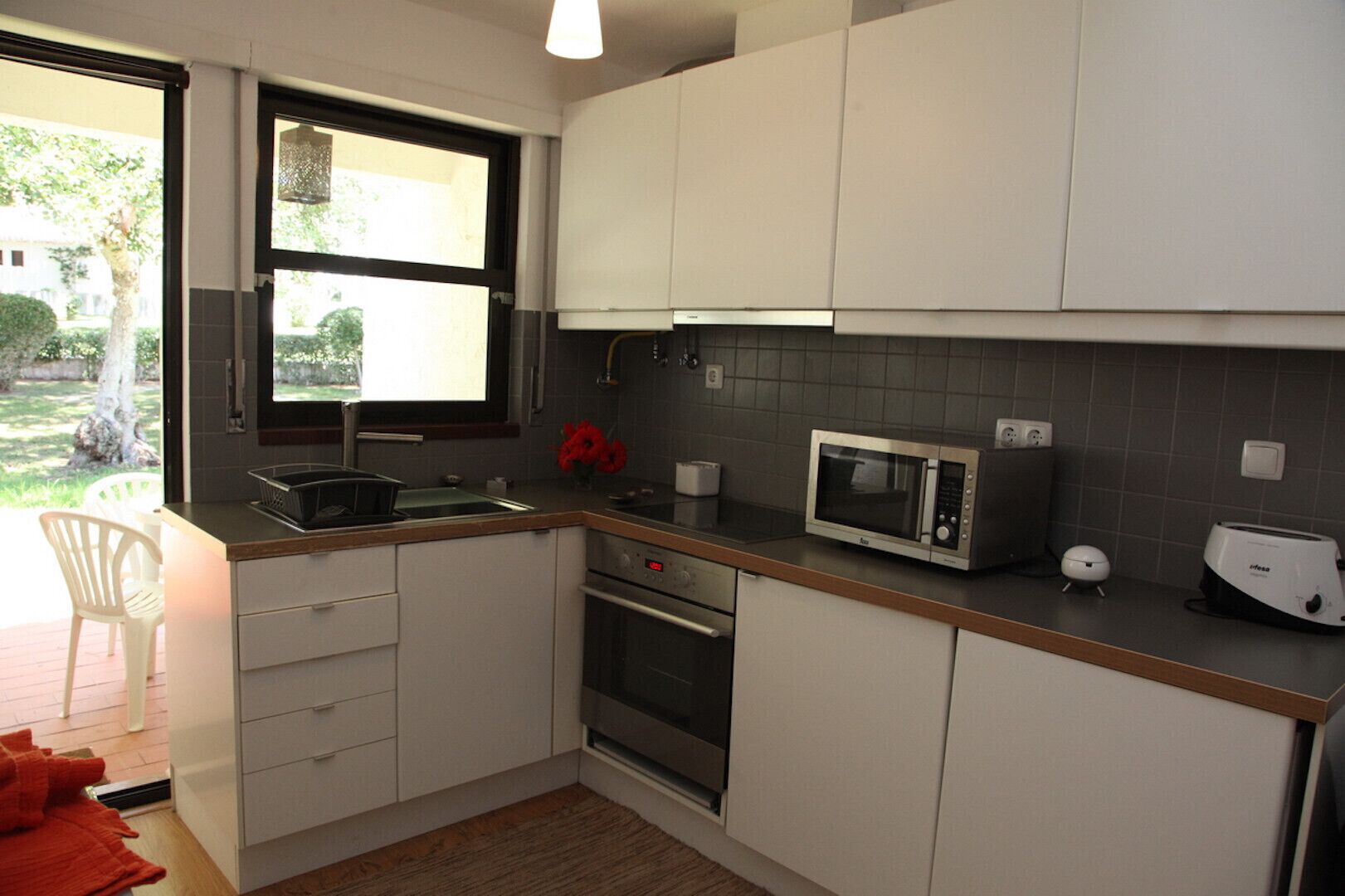 A modern kitchen with white cabinets, a microwave, a toaster, and a sink.