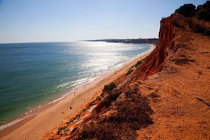 A coastal beach with a sandy shore and a steep cliff.