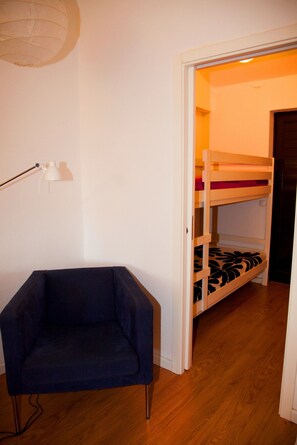 A room with a bunk bed, a desk chair, and a lamp.
