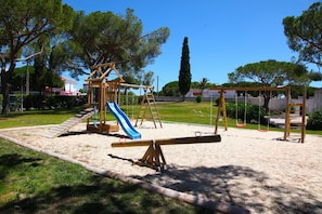 A playground with a seesaw, a slide, and swings.