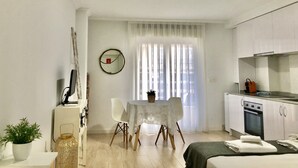 Habitació compacta i moderna amb una taula de dinar, una petita cuina i un llit.
