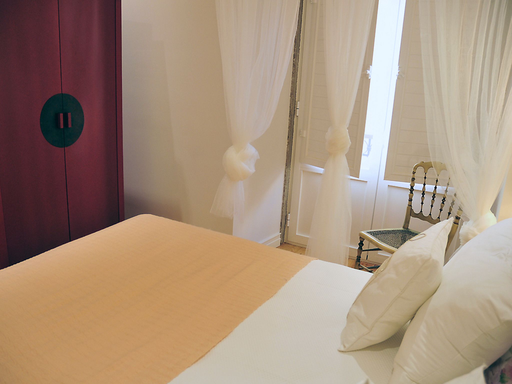 Un dormitorio con cama, una silla y un armario.
