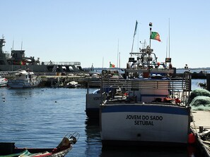 A harbor with several boats docked, including one with "JOVEM DO SADO SETÚBAL" written on its side.