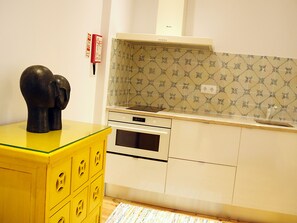 A kitchen with a yellow cabinet, a black sculpture, and patterned backsplash.